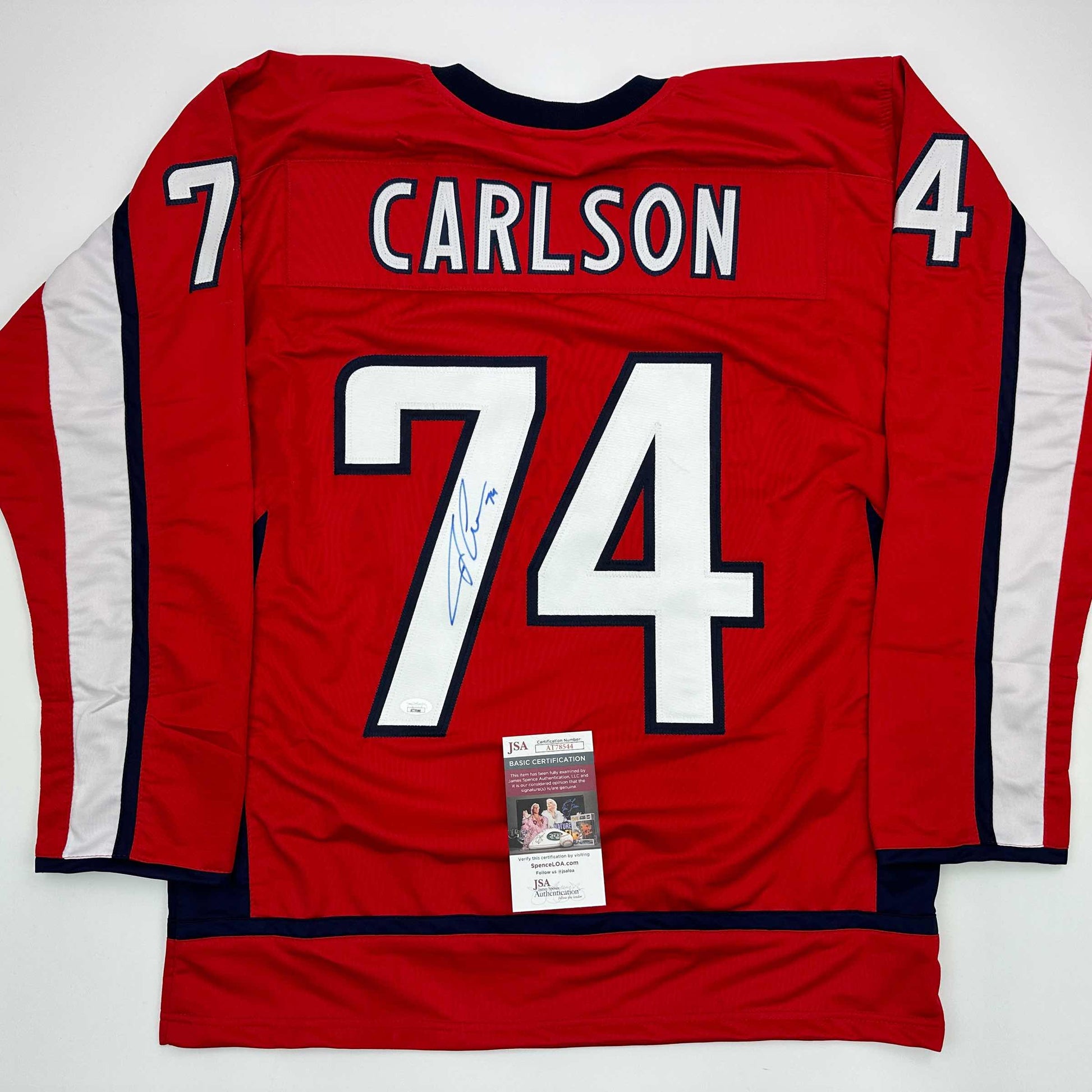 Red hockey jersey with "CARLSON" and number 74 on back, signed, with JSA authentication certificate attached.
