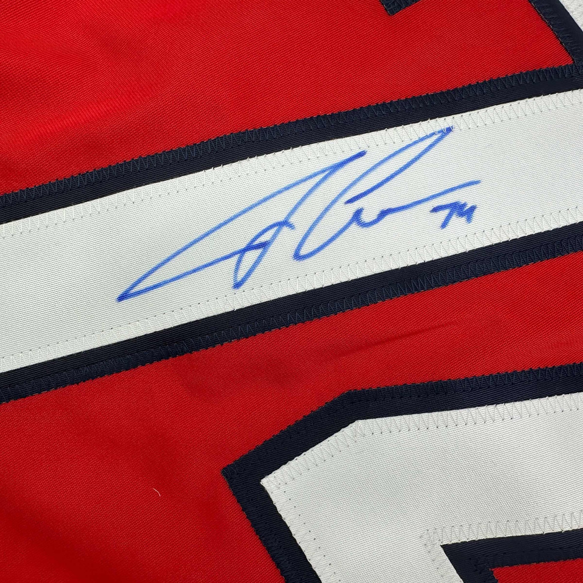 Close-up of blue autograph on white stripe of red, white, and black hockey jersey.