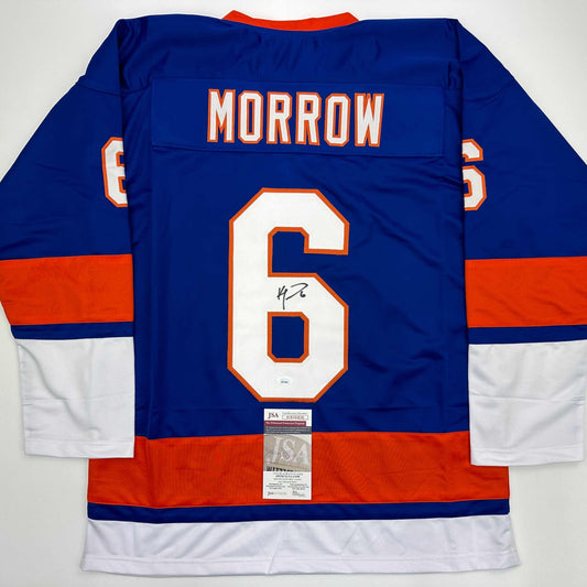 Back view of blue hockey jersey number 6 with "MORROW" nameplate, signed in black marker, featuring orange and white trim and JSA authentication certificate.