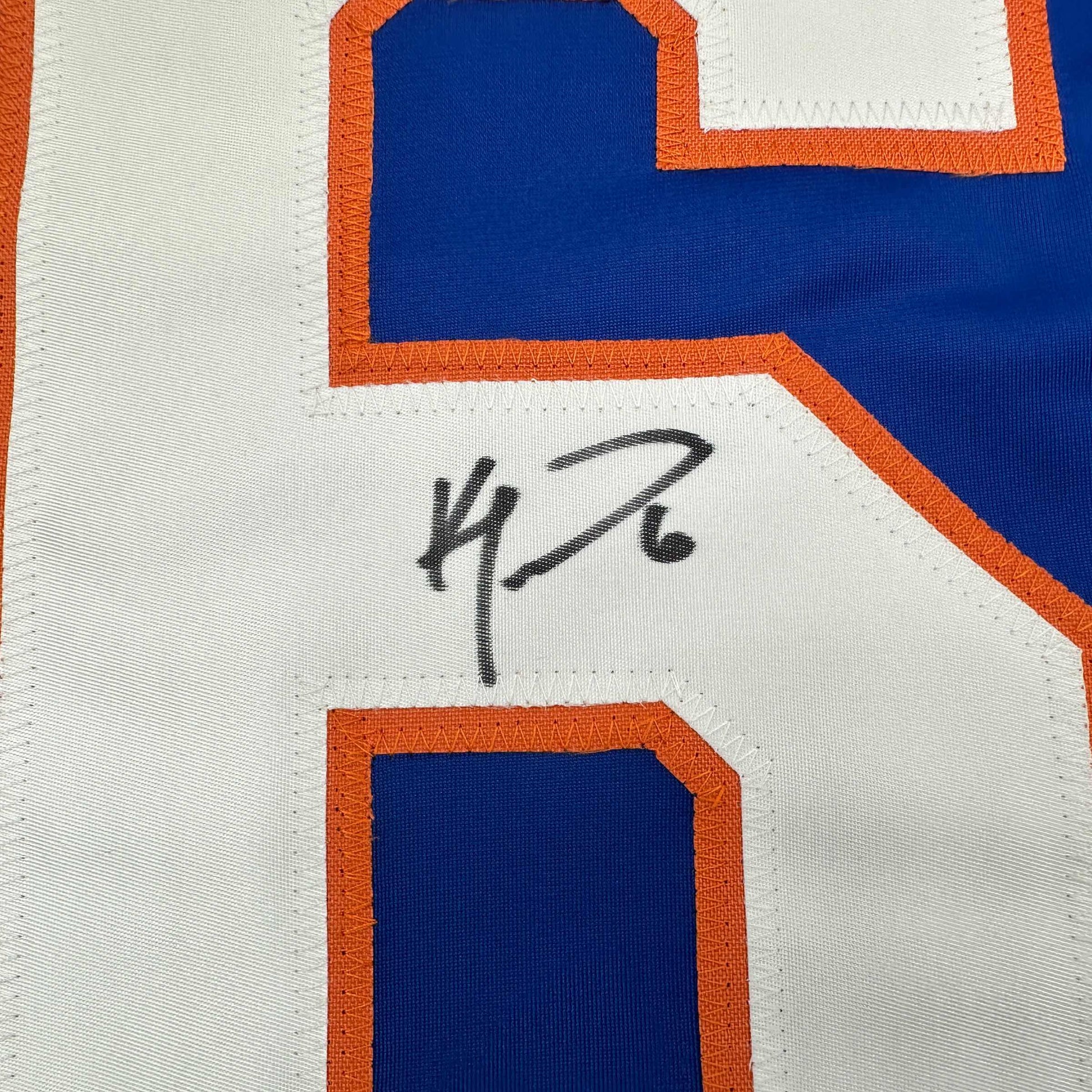 Close-up of Ken Morrow's handwritten signature on white fabric of orange and blue hockey jersey.
