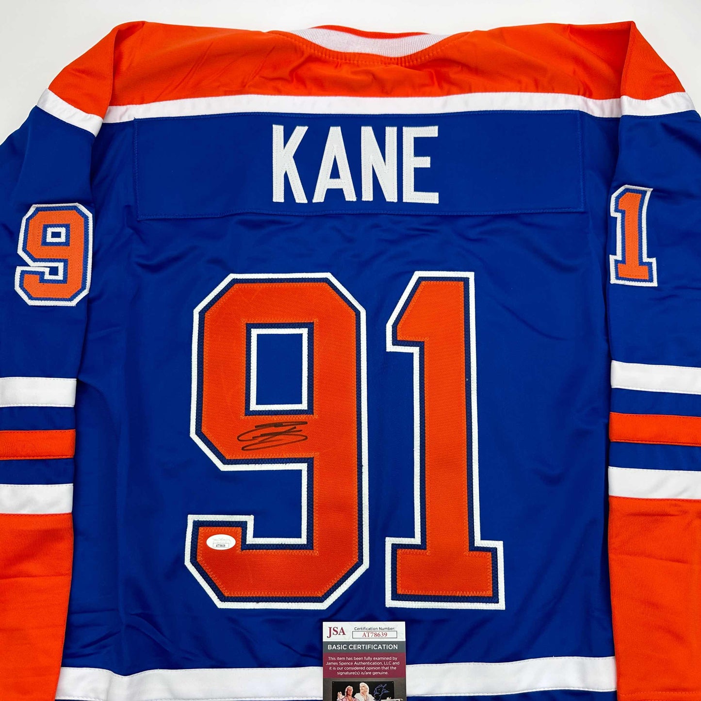 Back view of blue Edmonton Oilers hockey jersey with "KANE" and number 91 in orange and white, featuring JSA authentication certificate.