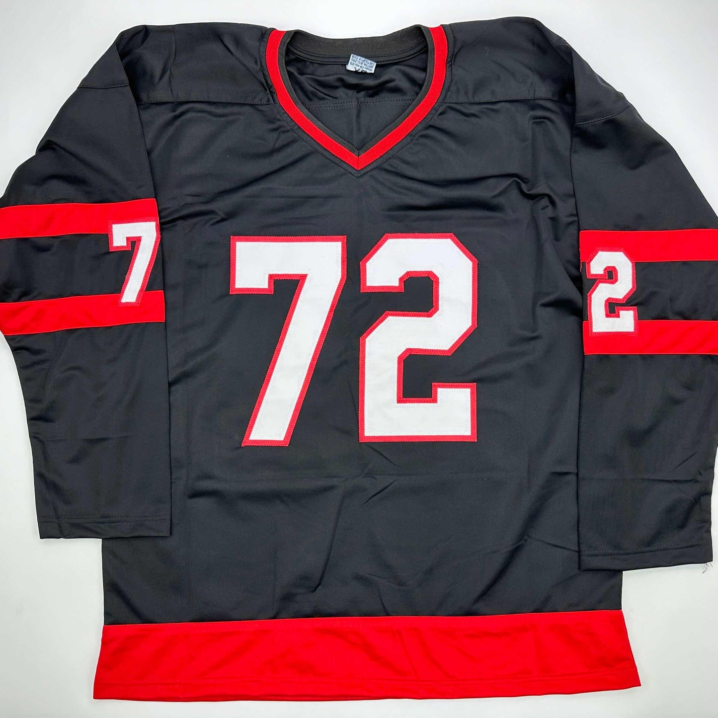 Black and red hockey jersey with white number 72 displayed flat against white background, showing front view with V-neckline and red horizontal stripes on sleeves and hem.
