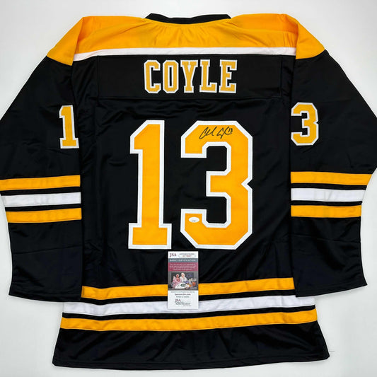 Back view of black Boston Bruins hockey jersey number 13 with "COYLE" nameplate, signed, displaying yellow and white stripes with JSA authentication certificate.