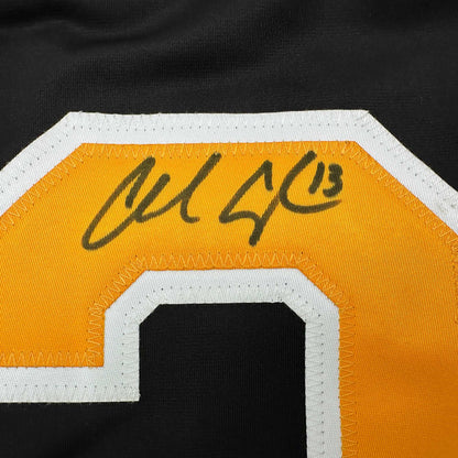 Close-up of autographed gold and white hockey jersey showing handwritten signature on orange fabric with white trim.