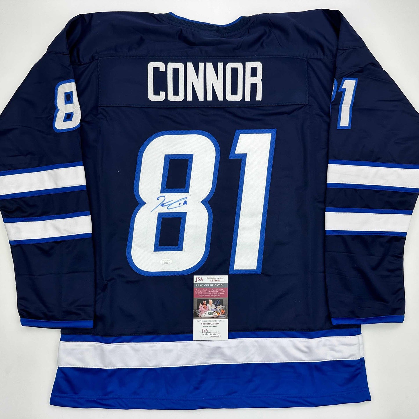Back view of navy blue Winnipeg Jets hockey jersey number 81 with "CONNOR" nameplate and signed number 8, displaying white and blue stripes on sleeves with JSA authentication certificate.