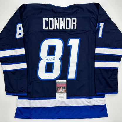 Back view of navy blue Winnipeg Jets hockey jersey number 81 with "CONNOR" nameplate and signed number 8, displaying white and blue stripes on sleeves with JSA authentication certificate.