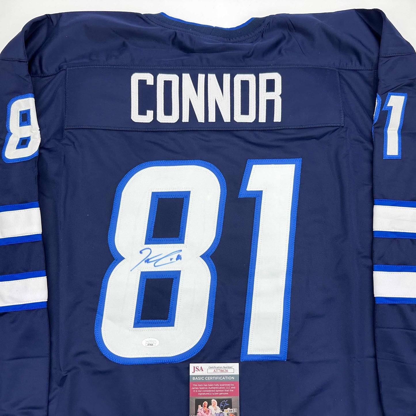 Back view of navy blue hockey jersey with "CONNOR" and number "81" in white and blue lettering, featuring blue and white striped sleeves and JSA authentication label.
