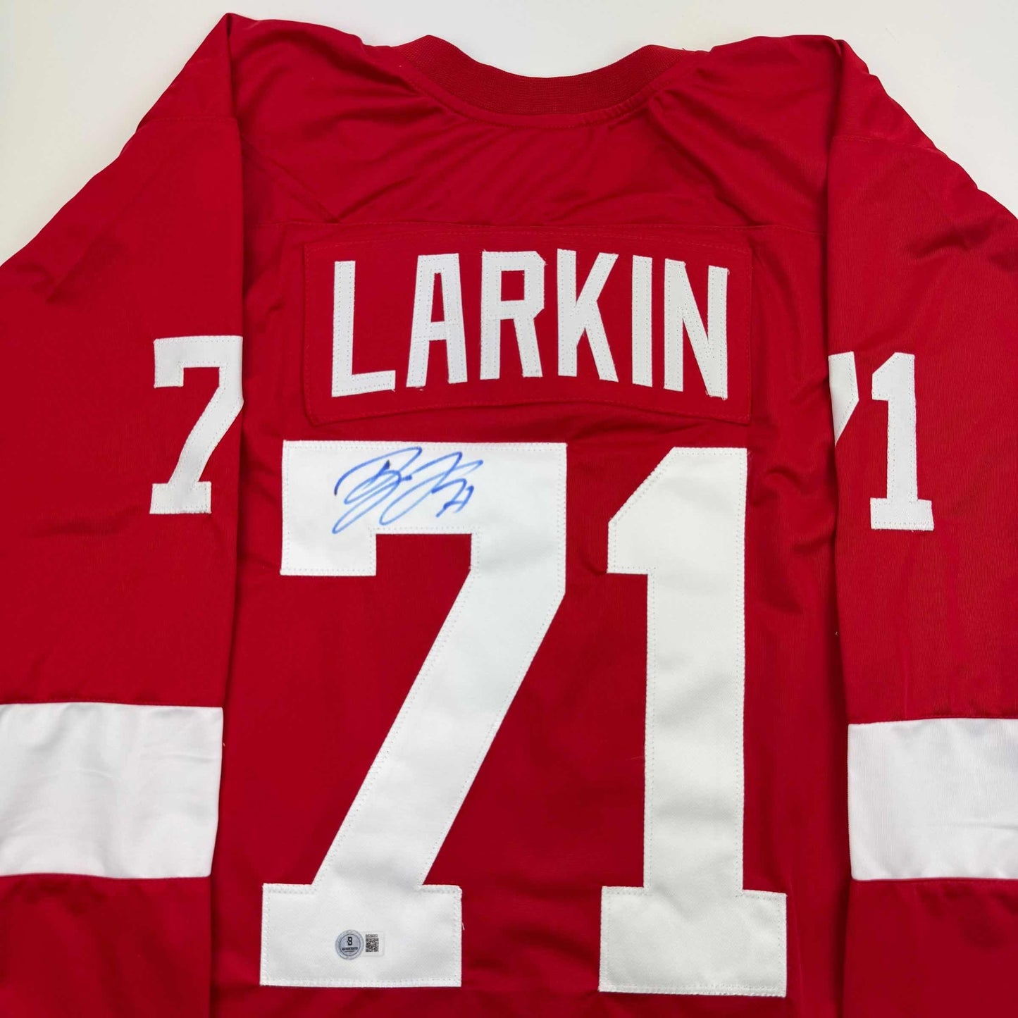 Red Detroit Red Wings hockey jersey displaying "LARKIN" and number 71 with blue autograph signature on white chest panel.