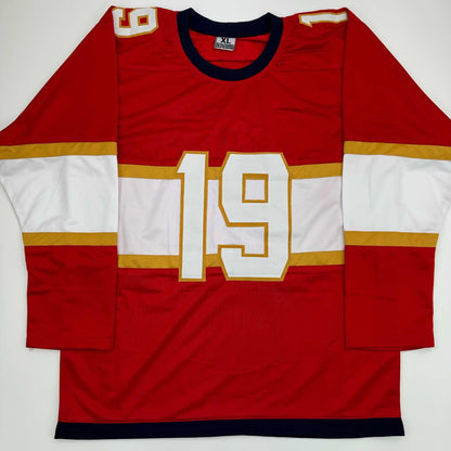 Red and white hockey jersey with gold trim and number 19 displayed flat against white background, front view.