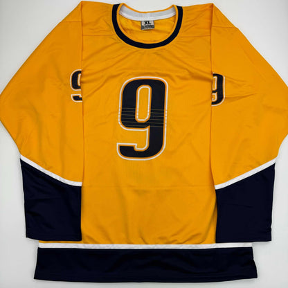 Yellow hockey jersey with number 9, black and white trim, displayed flat against white background.