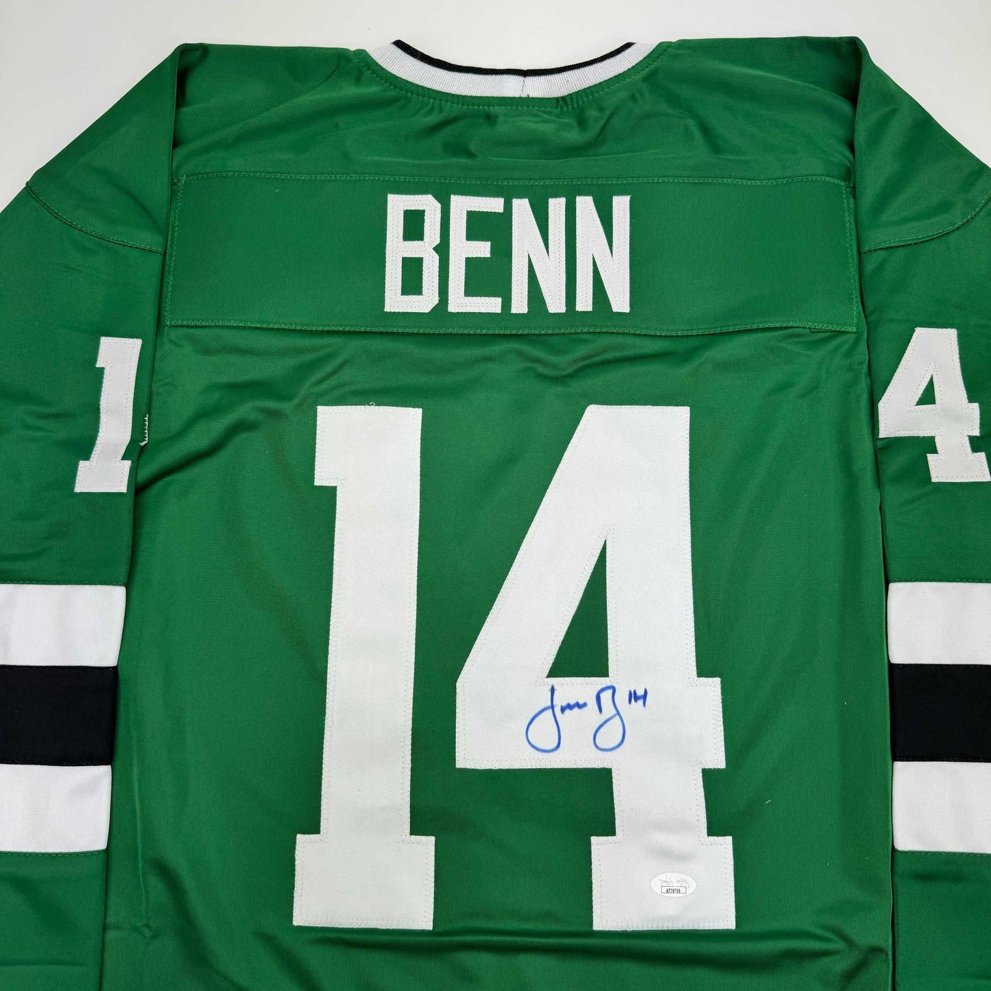 Back view of green hockey jersey with white number 14, "BENN" nameplate, and blue autograph signature on the number.