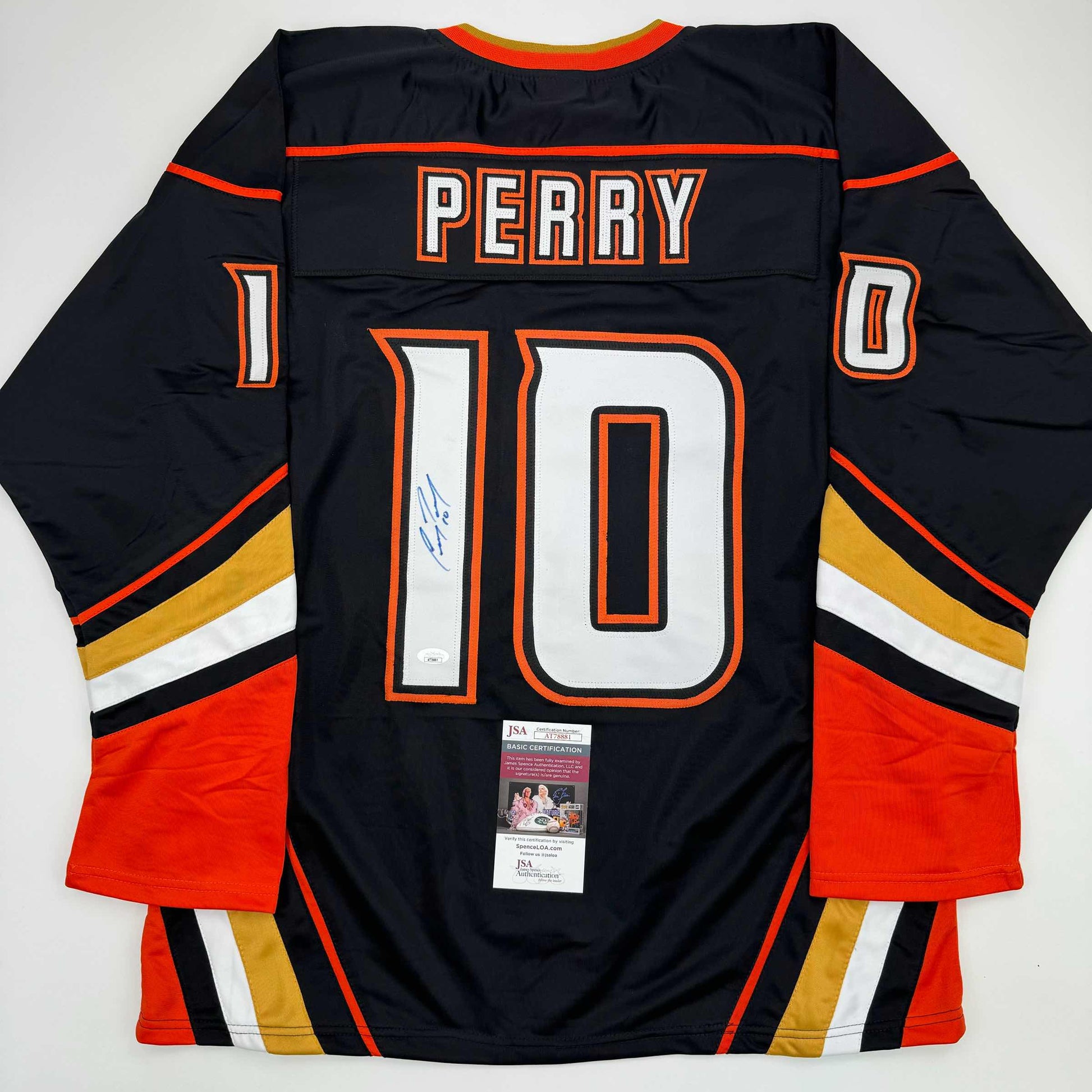 Back view of signed black Anaheim Ducks hockey jersey number 10 with Perry nameplate, red and gold striping, and JSA authentication certificate.