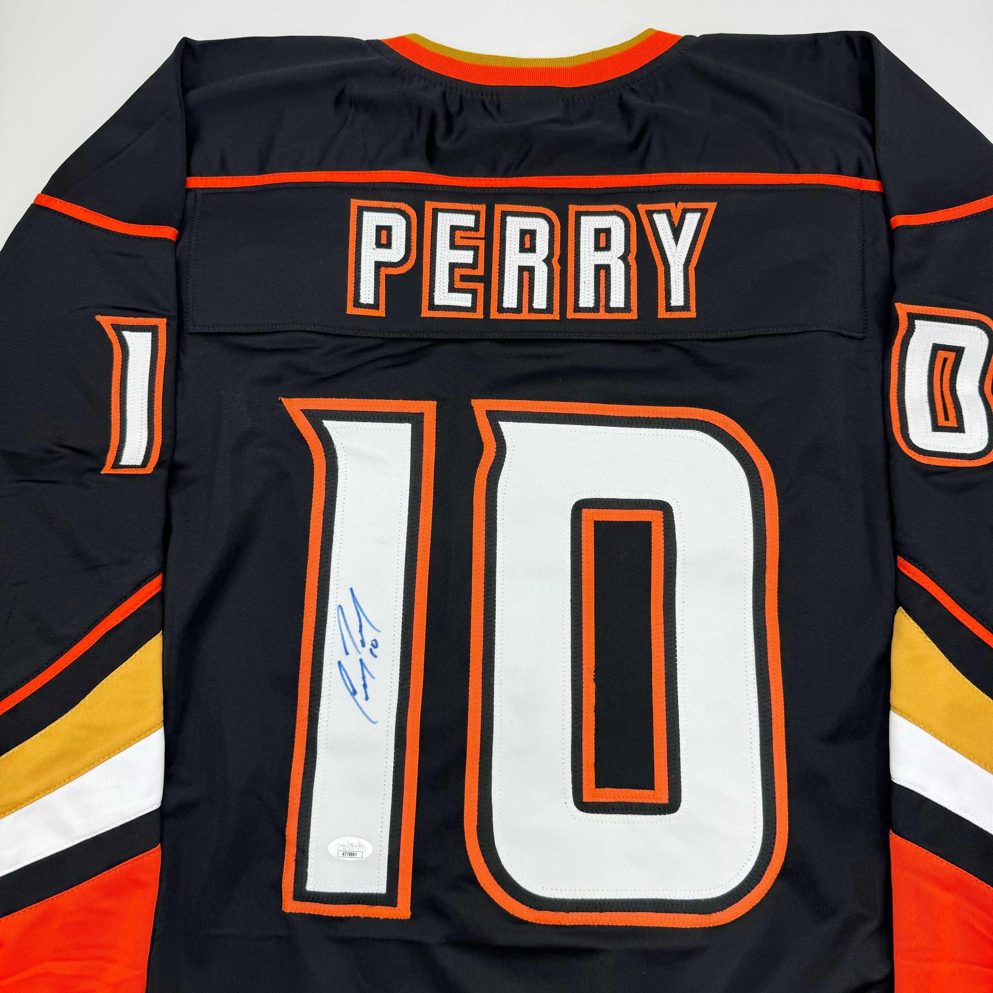 Back view of black Anaheim Ducks hockey jersey number 10 with "PERRY" nameplate and blue signature on white number.