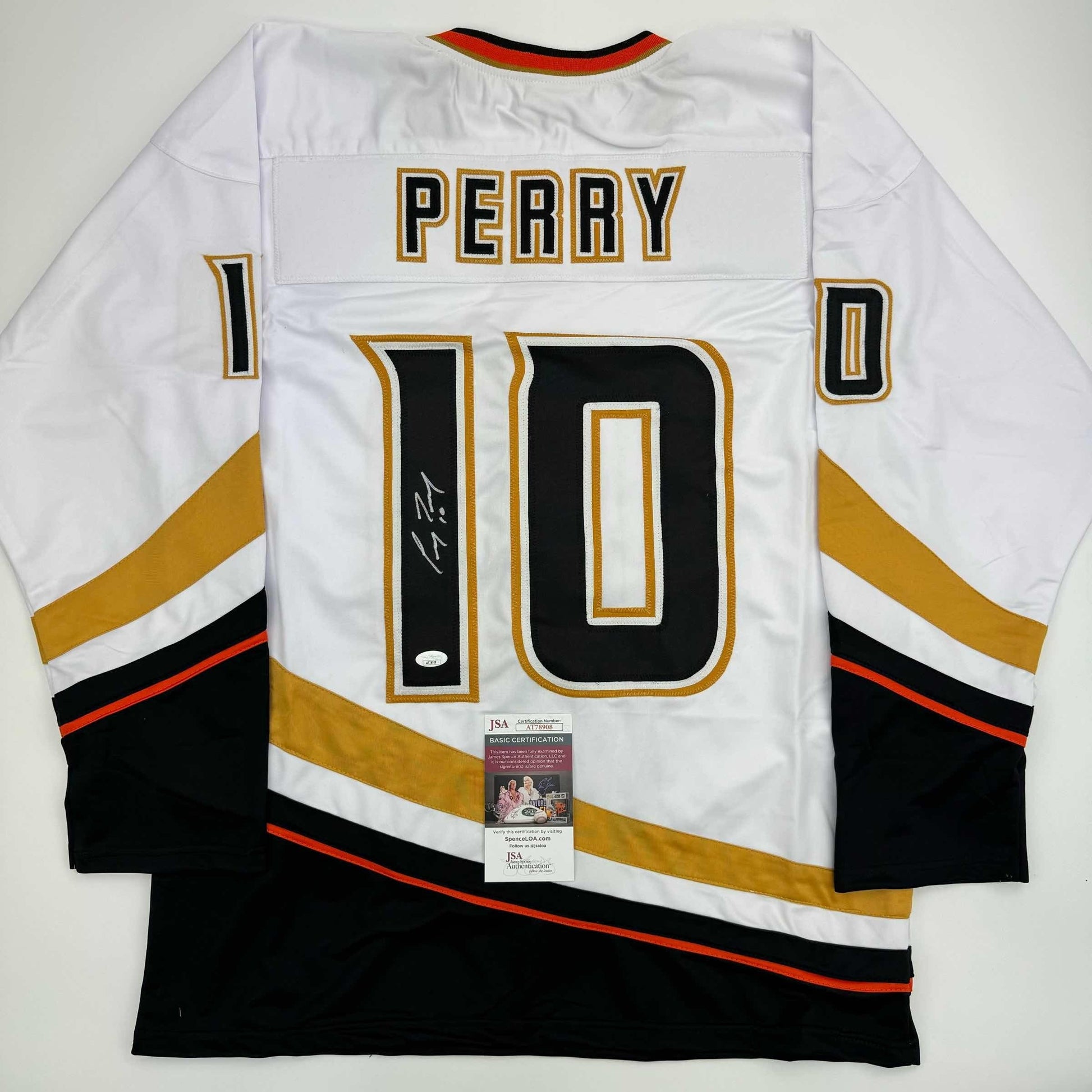 White Anaheim Ducks hockey jersey number 10 with "PERRY" nameplate, signed, displayed flat with JSA authentication certificate visible.