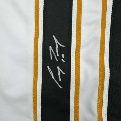 Close-up of autographed black stripe on white hockey jersey showing handwritten signature in silver ink.