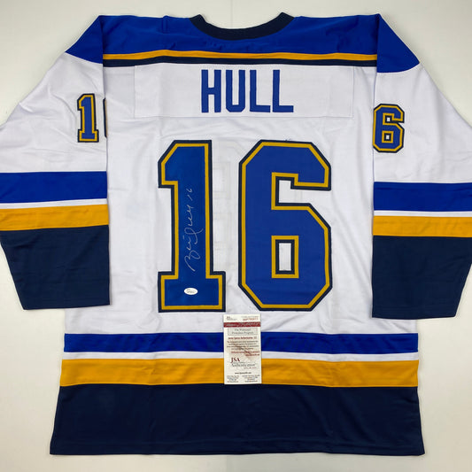 Signed white St. Louis Blues hockey jersey number 16 with Hull nameplate, displayed flat with JSA authentication certificate visible.