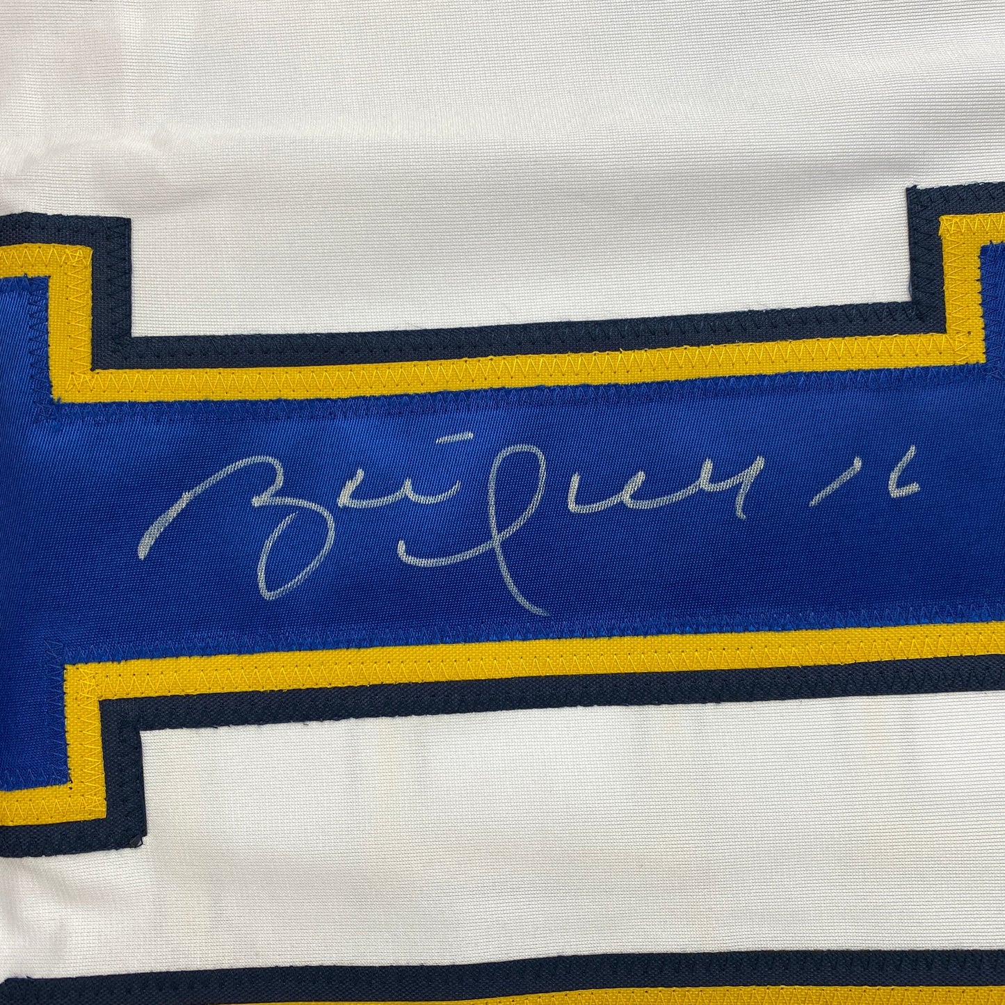 Close-up of Brett Hull's handwritten signature in silver ink on blue jersey stripe with navy and gold trim.
