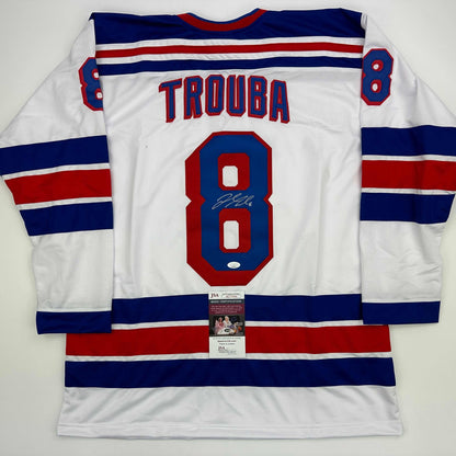 Back view of white hockey jersey with navy and red stripes, number 8, "TROUBA" nameplate, and JSA authentication certificate attached.