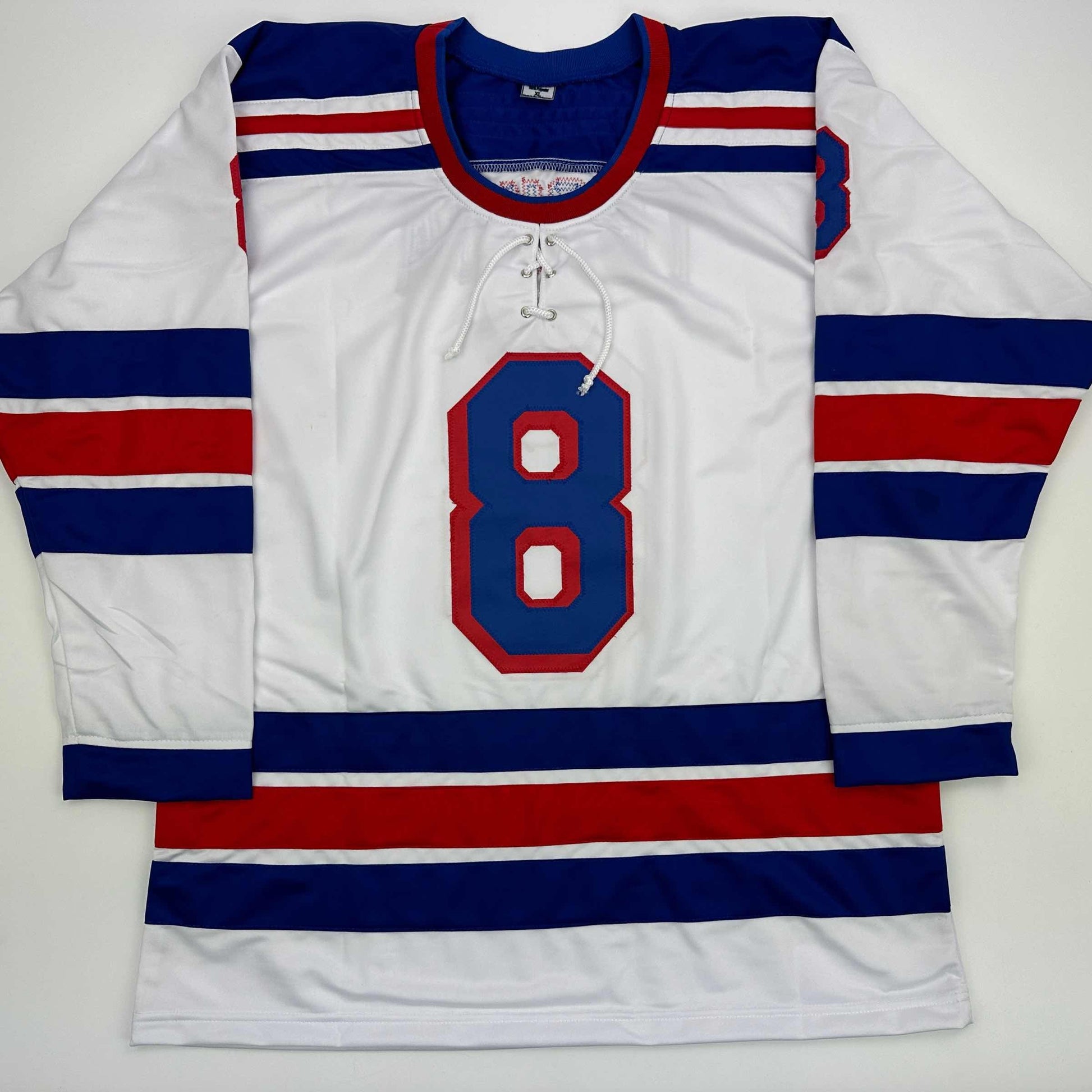 White hockey jersey with navy blue and red horizontal stripes, number 8 in blue with red outline on chest, displayed flat against white background.