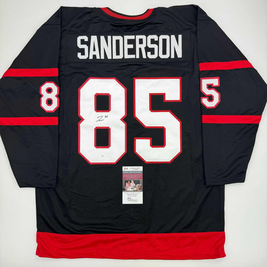 Back view of black and red Ottawa Senators hockey jersey #85 with "SANDERSON" nameplate and JSA authentication certificate visible.