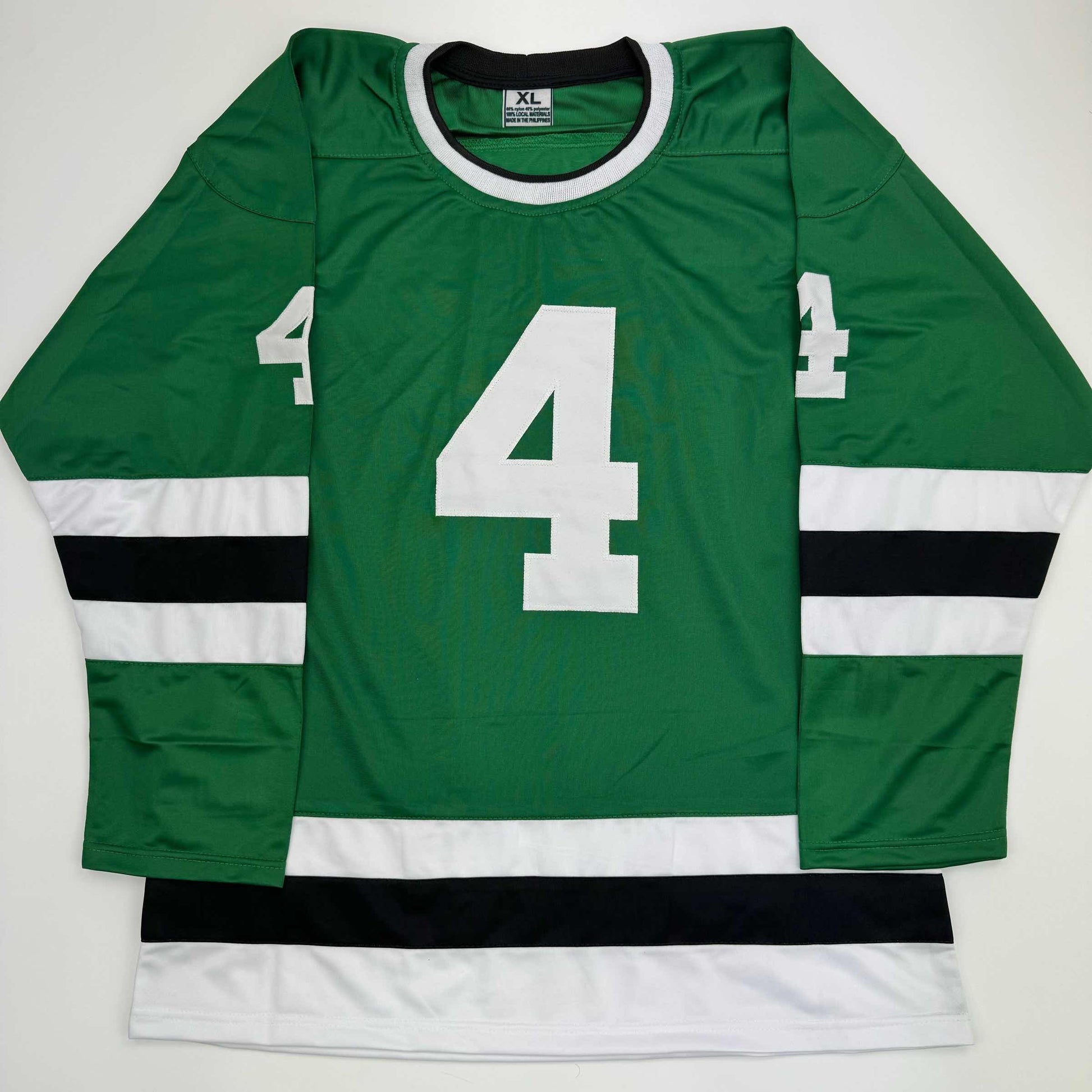 Flat lay of green, white, and black hockey jersey with large white number 4 on chest and sleeves.