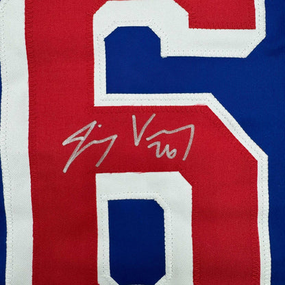 Close-up of red jersey number 16 with silver autograph "Jimmy Vesey" on white-trimmed fabric.