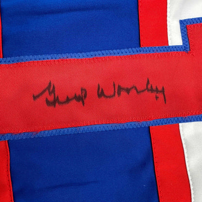 Close-up of red fabric stripe with black handwritten signature on blue and red striped hockey jersey.