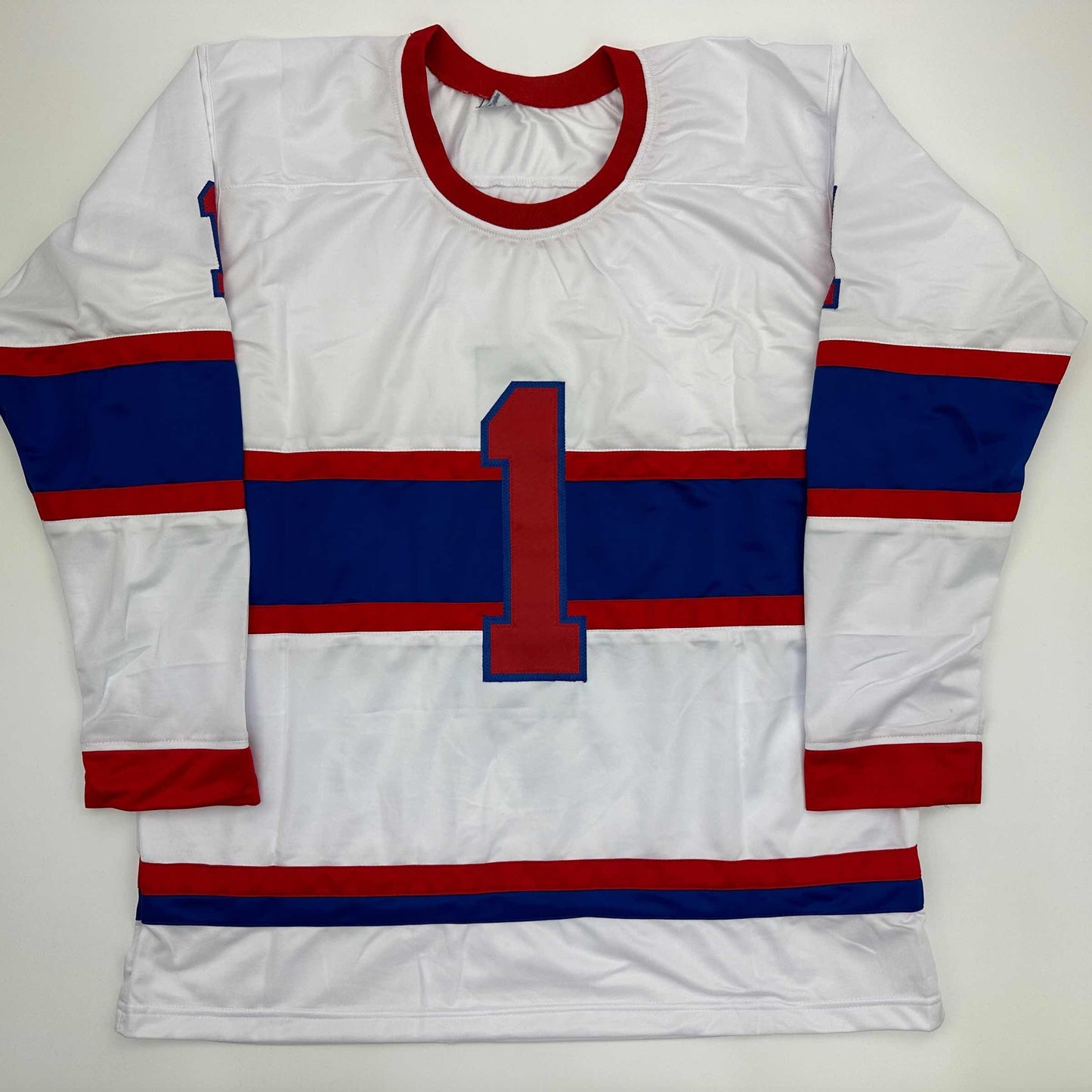 White, red, and blue striped hockey jersey with large red number 1 displayed flat against neutral background.