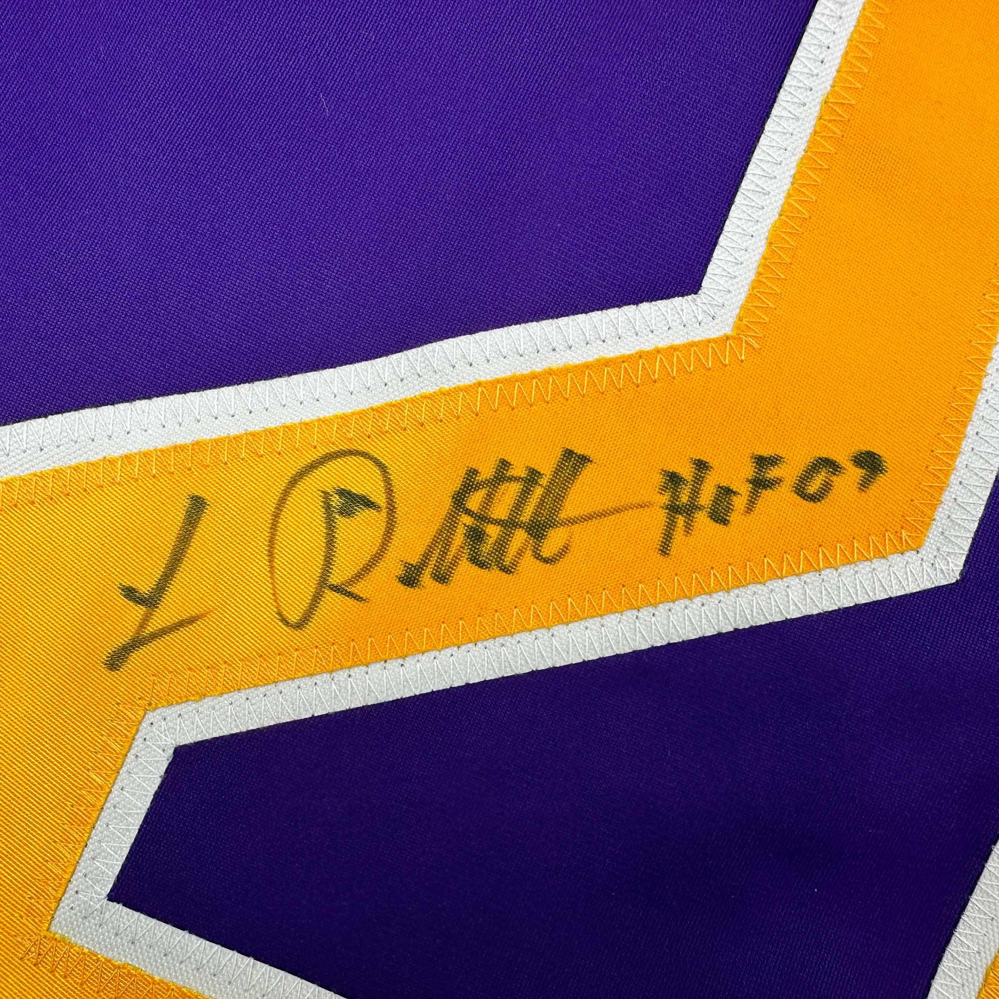 Close-up of signed yellow stripe on purple and gold hockey jersey showing "Luc Robitaille HOF 09" autograph in black ink.