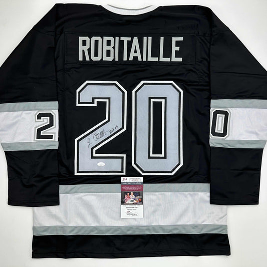 Back view of signed black and white hockey jersey #20 with ROBITAILLE nameplate and JSA authentication certificate visible.