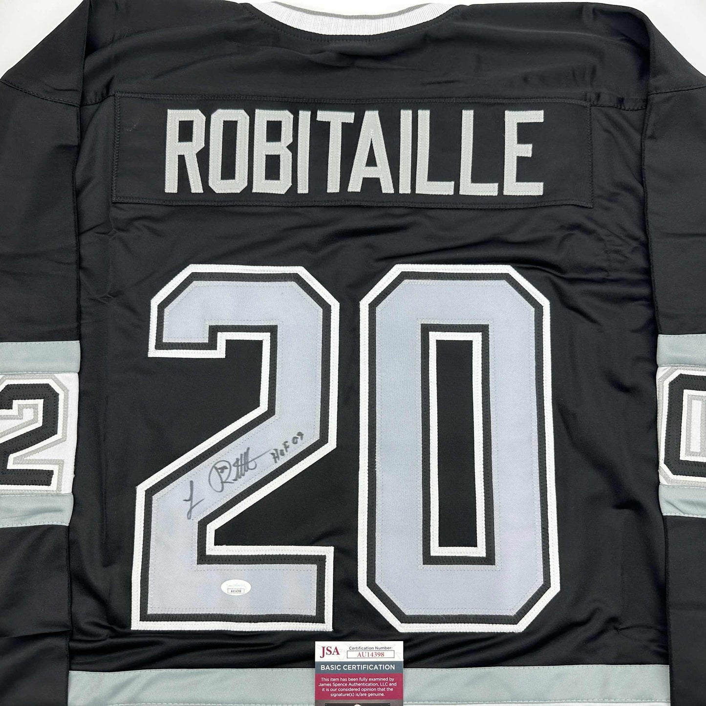 Back view of black hockey jersey displaying "ROBITAILLE" and number "20" in white with signature and JSA certification label visible.