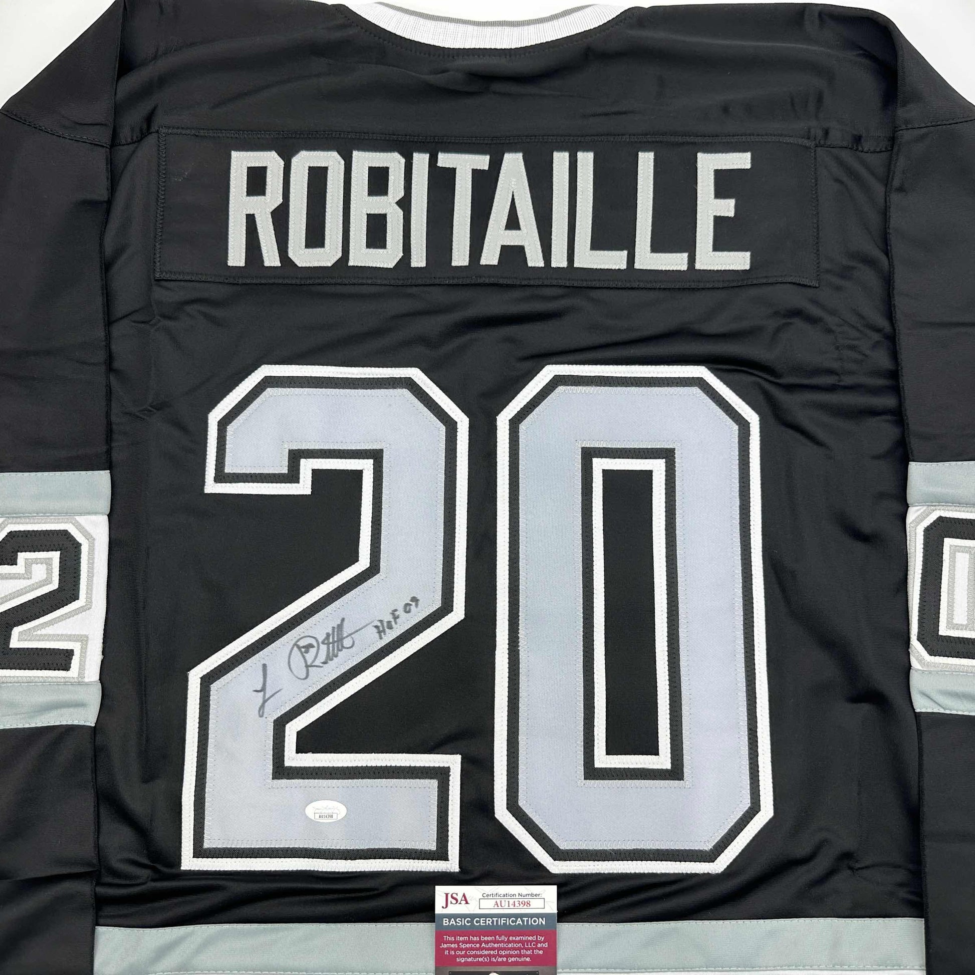 Back view of black hockey jersey displaying "ROBITAILLE" and number "20" in white with signature and JSA certification label visible.