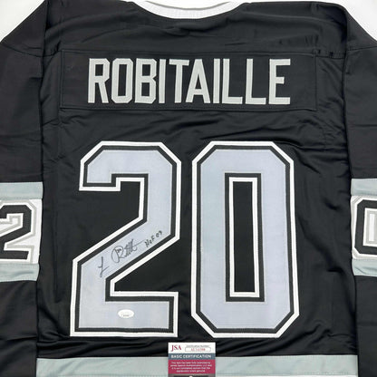 Back view of black hockey jersey displaying "ROBITAILLE" and number "20" in white with signature and JSA certification label visible.