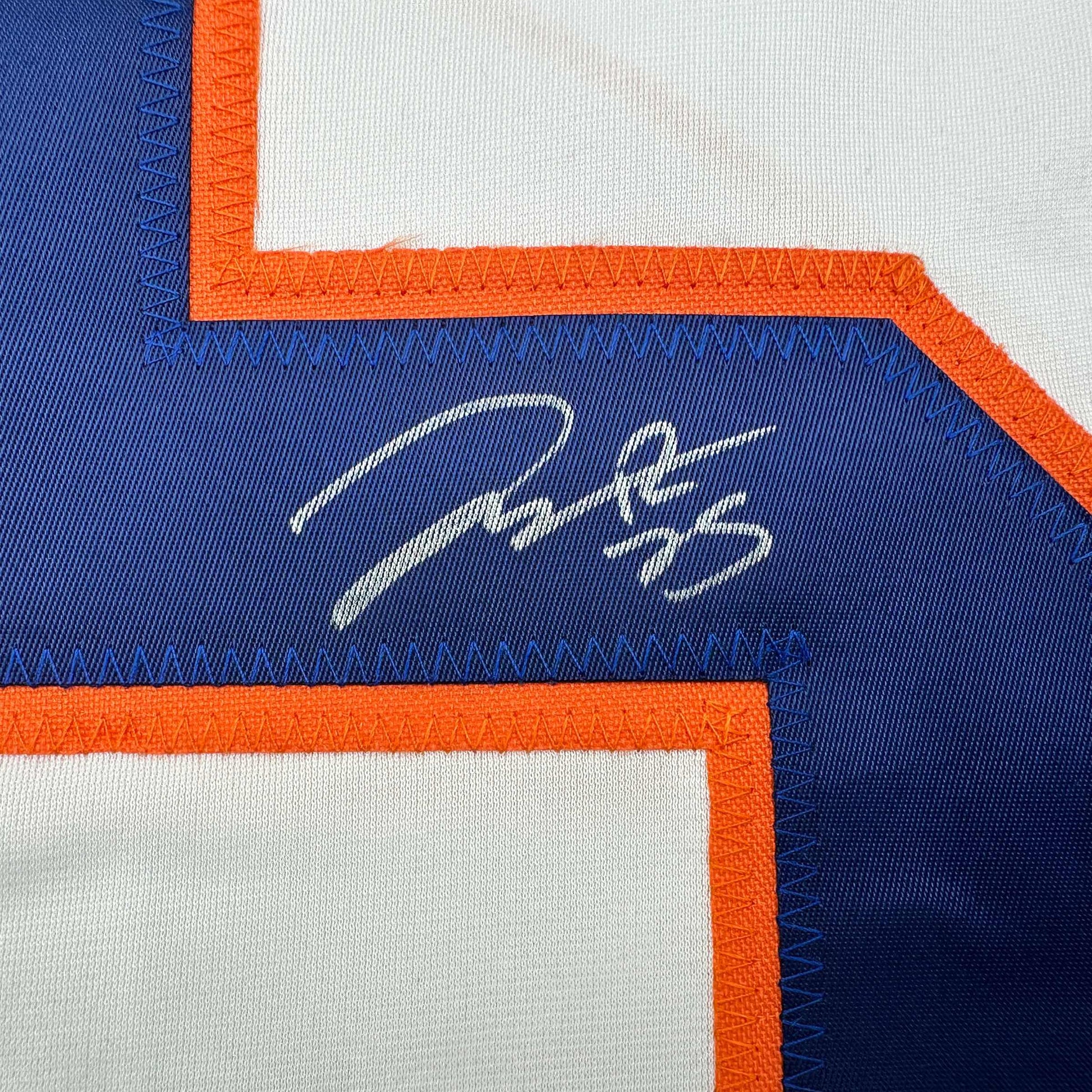 Close-up of embroidered signature on blue Edmonton Oilers hockey jersey with orange and white trim.