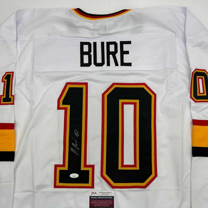 Back view of white hockey jersey displaying "BURE" nameplate and number "10" with red and gold trim, signed in black marker, JSA authentication sticker visible.