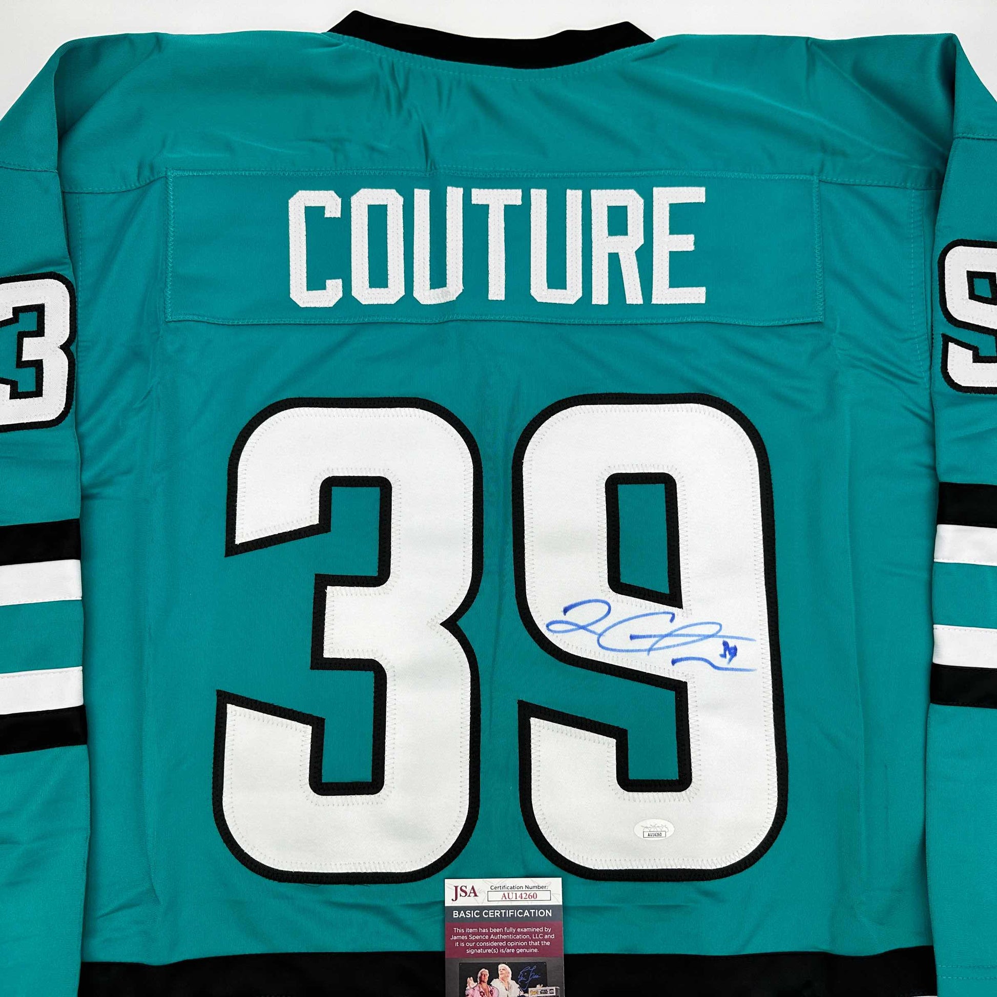 Back view of teal hockey jersey number 39 with "COUTURE" nameplate and blue autograph, JSA certification sticker visible.