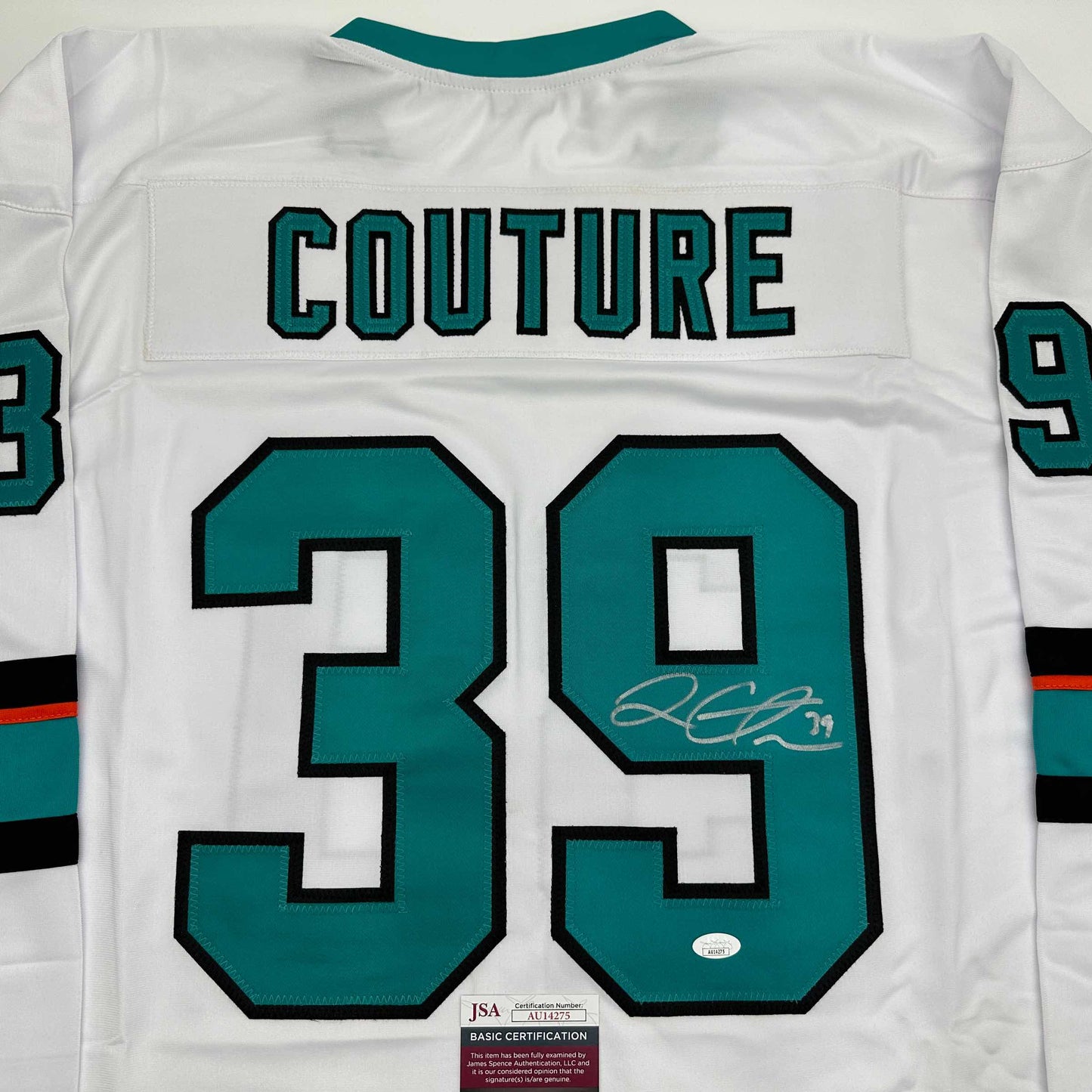 Back view of white hockey jersey with teal and black number 39, "COUTURE" text, and autographed signature with JSA certification label.