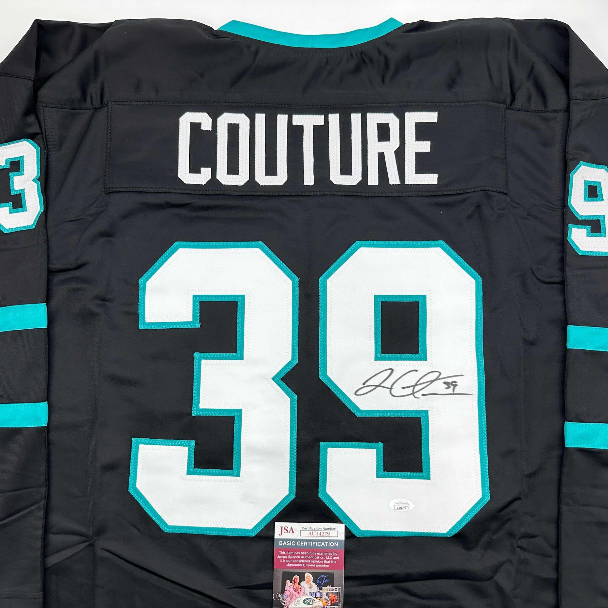 Back view of black hockey jersey with turquoise and white number 39, "COUTURE" nameplate, and autograph with JSA certification sticker.