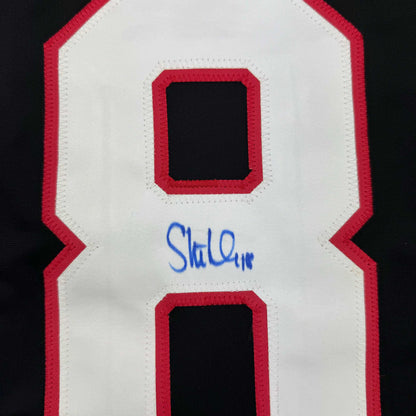Close-up of red and white hockey jersey back showing number 8 with blue autograph signature below.