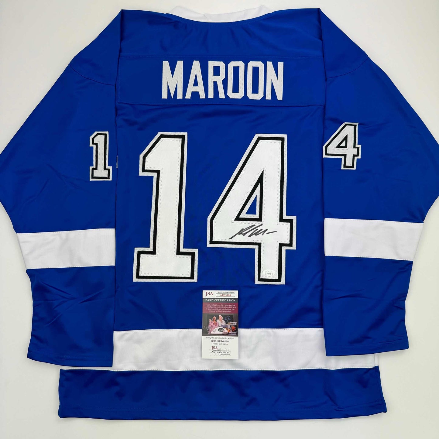 Back view of blue hockey jersey displaying "MAROON" and number "14" with white lettering and JSA authentication certificate attached.