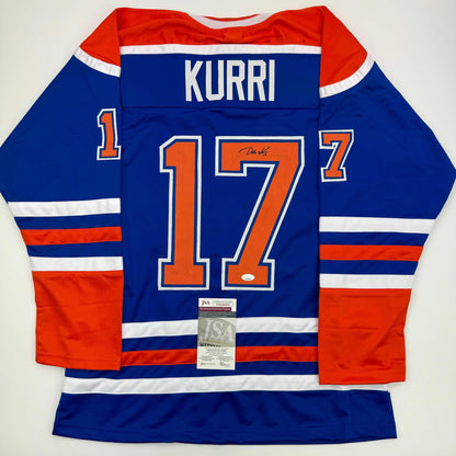 Signed blue Edmonton Oilers hockey jersey number 17 with "KURRI" nameplate displayed flat, back view showing JSA authentication certificate.