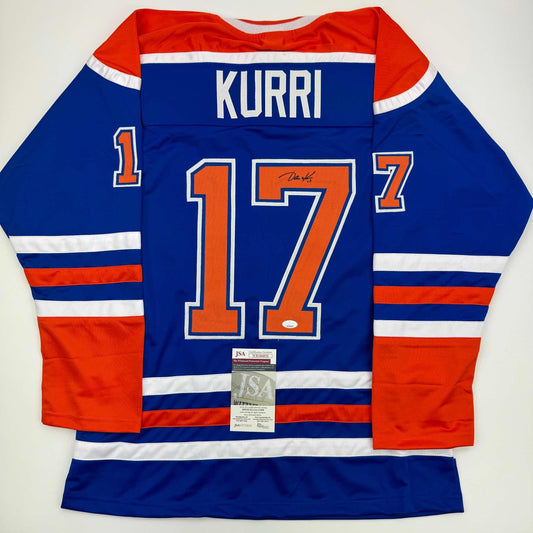 Signed blue Edmonton Oilers hockey jersey number 17 with "KURRI" nameplate displayed flat, back view showing JSA authentication certificate.