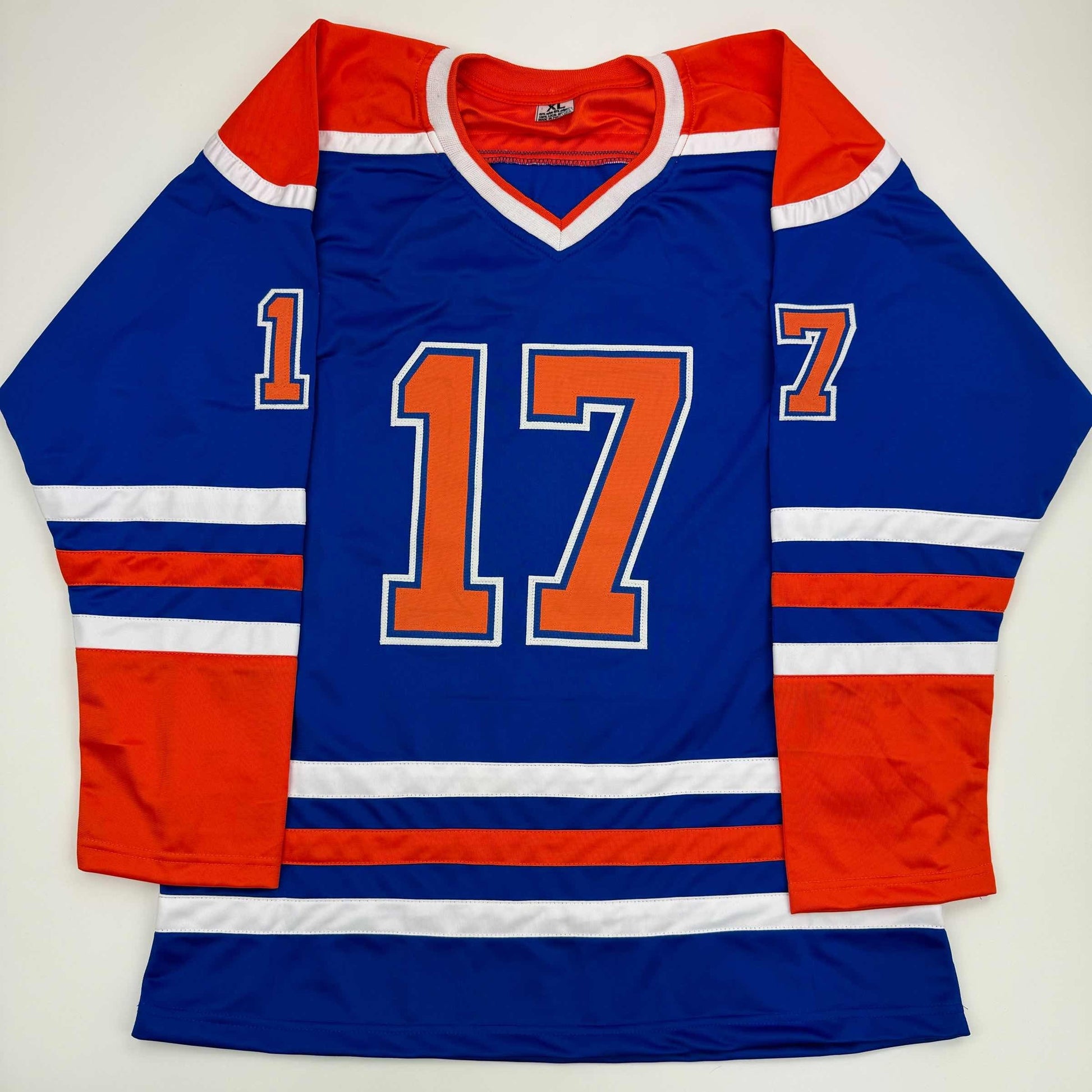 Blue Edmonton Oilers hockey jersey with red and white stripes, orange number 17, displayed flat on white background.