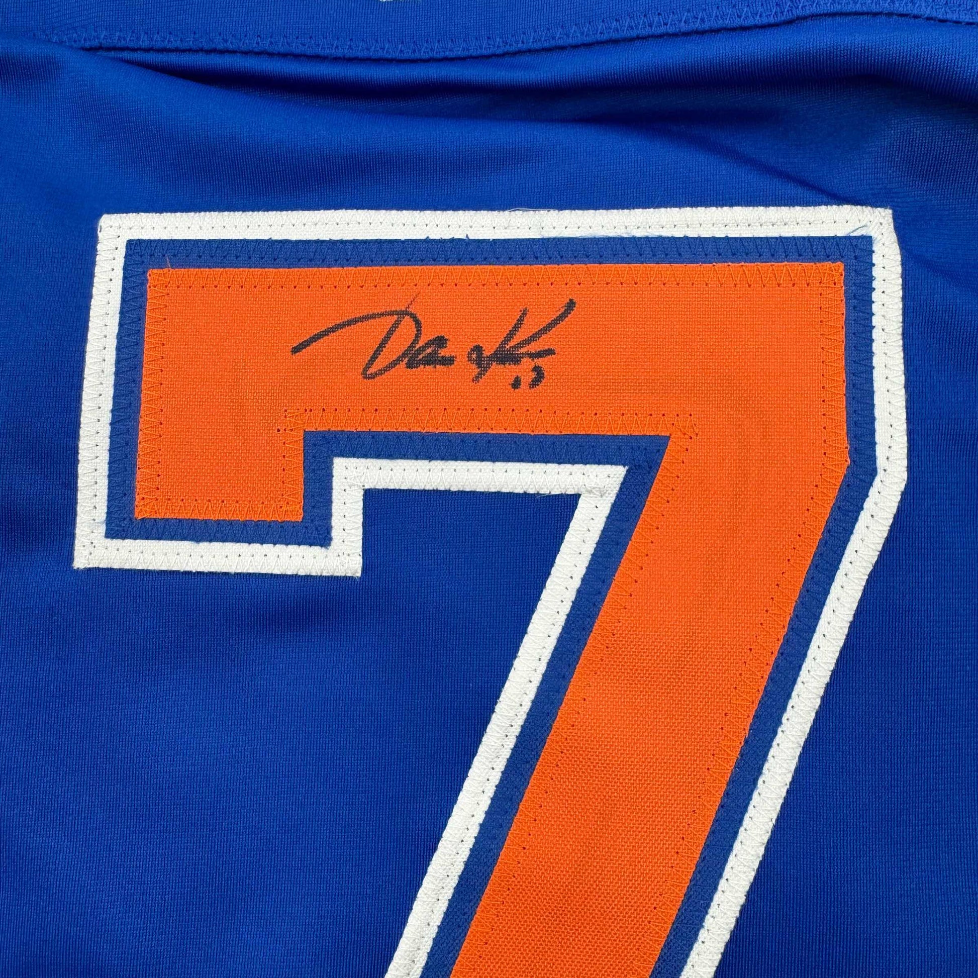 Close-up of signed orange number 7 on blue Edmonton Oilers hockey jersey with white trim.