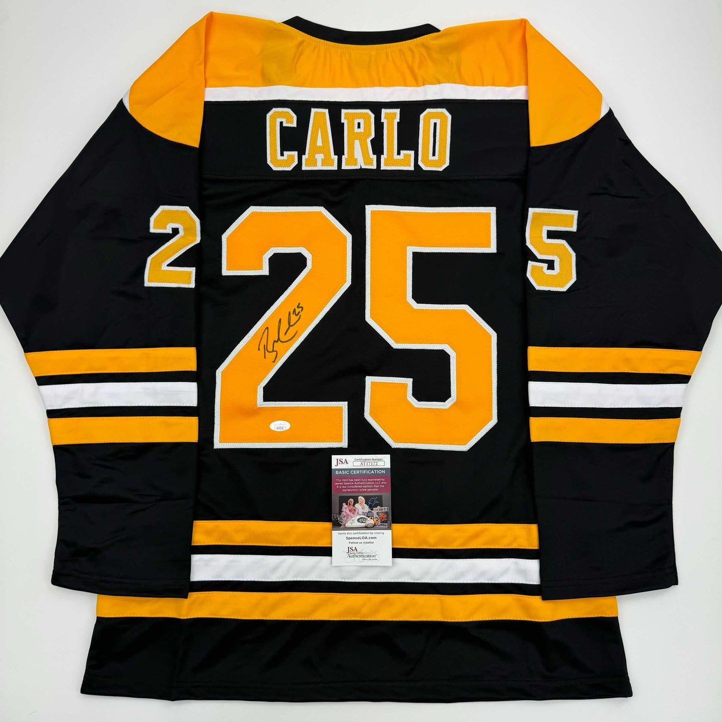 Back view of black and gold Boston Bruins hockey jersey number 25 with "Carlo" nameplate and signature, JSA authentication certificate visible.