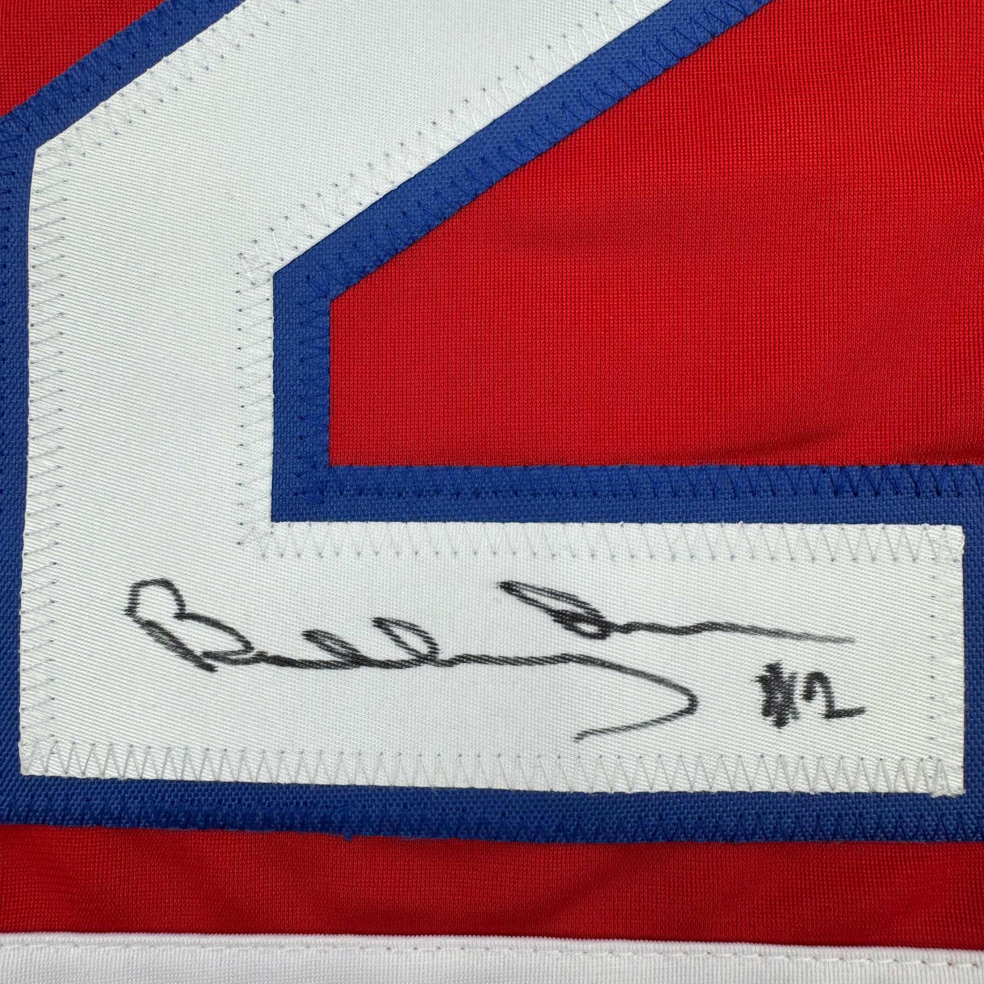 Close-up of handwritten signature on white fabric label of red, white, and blue striped hockey jersey.