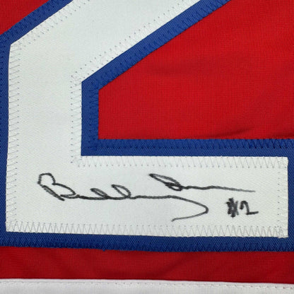 Close-up of handwritten signature on white fabric label of red, white, and blue striped hockey jersey.