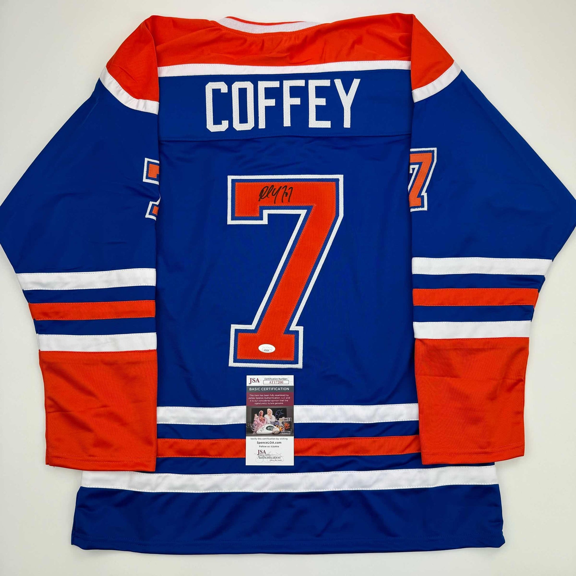 Back view of signed blue Edmonton Oilers jersey number 7 with "COFFEY" nameplate and JSA authentication certificate visible.