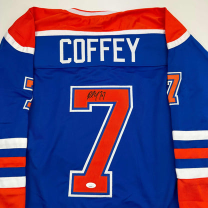 Back view of blue Edmonton Oilers hockey jersey with "COFFEY" nameplate and number 7 in red, autographed in black marker.