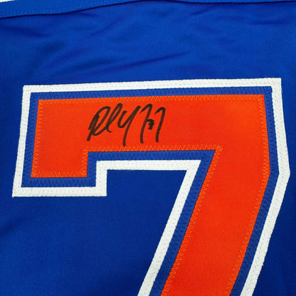 Close-up of autographed number 7 on blue hockey jersey with orange and white trim, showing signature in black ink.